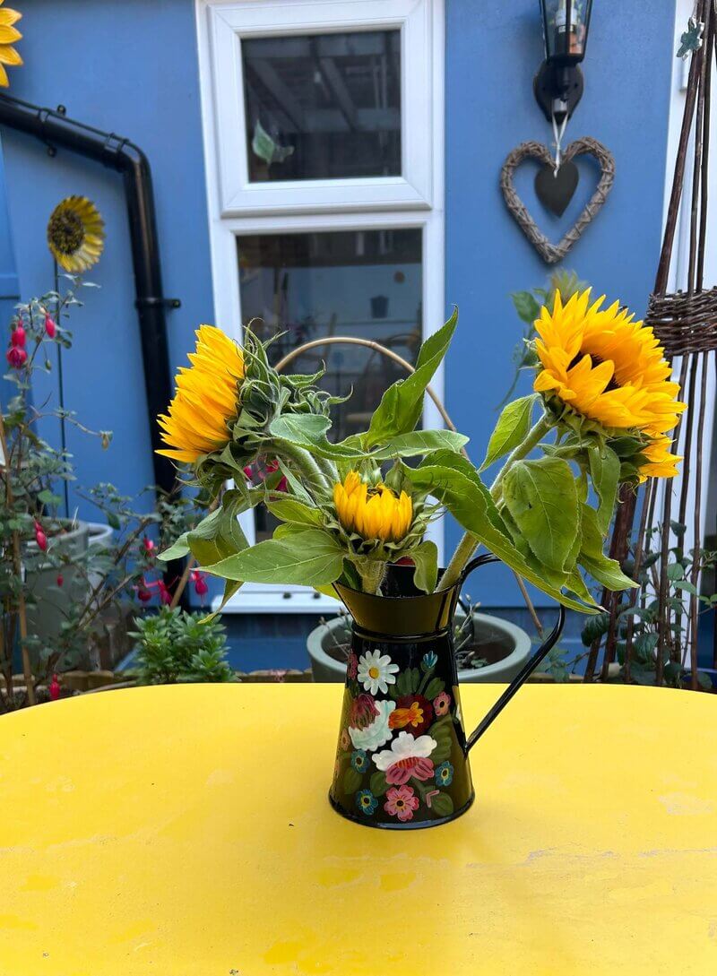 A bunch of Sunflowers in a decorated vase in front of 'The Sunflower House'. The Sunflower House is the play therapy practice room for 'Turn To The Sun Play Therapy'.