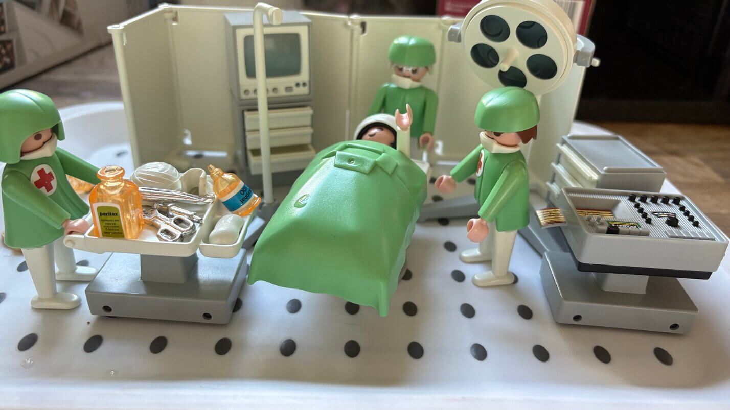 Toy doctors and nurses attending to a patient with miniature medical tools and supplies
